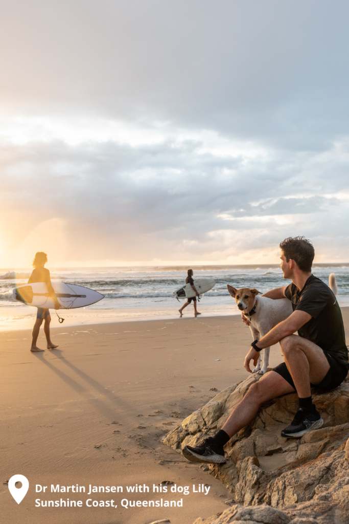 Vet Martin Jansen on the beach with his dog with surfers in the backgroun.