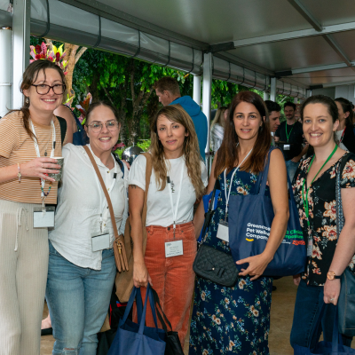 5 people standing in the exhibition hall smiling at the camera, they are holding showbags